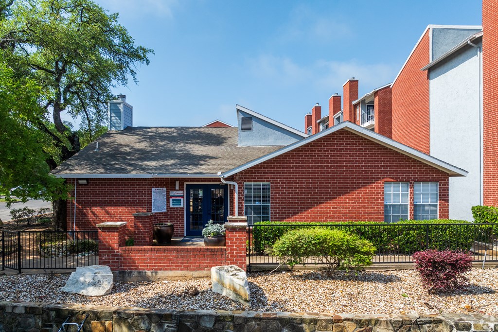 A red brick house with a black fence and a small garden in front.