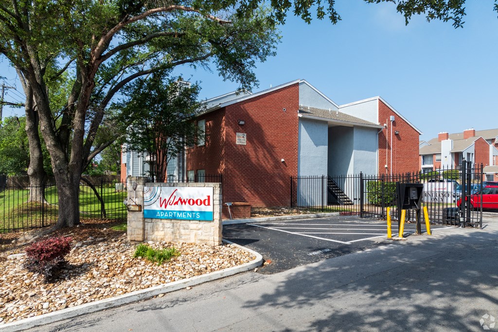 A brick building with a sign that says "Wilwood Apartments" in front of it.
