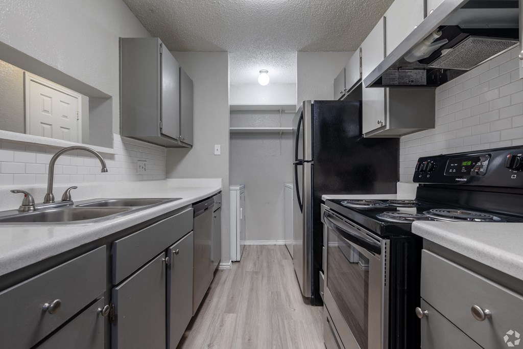 A kitchen with a black refrigerator and stove top oven.