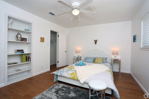 A bedroom with a bed, a chair, and a ceiling fan.