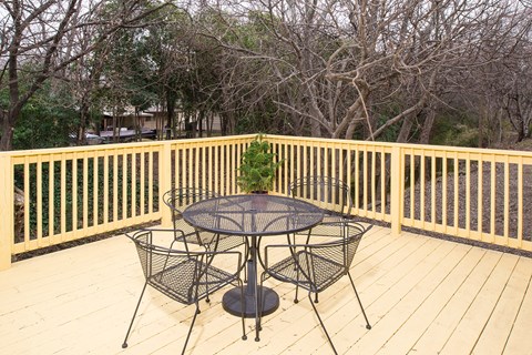 Outdoor deck with seating and wooden railing at Creekline Apartments, Austin, 78757