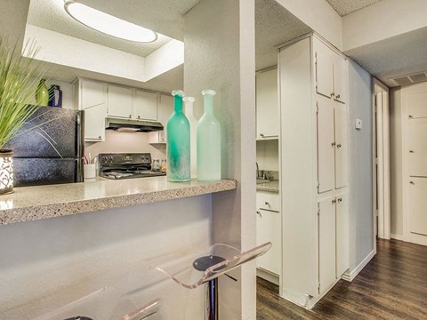 a kitchen with white cabinets and a counter with bottles on it