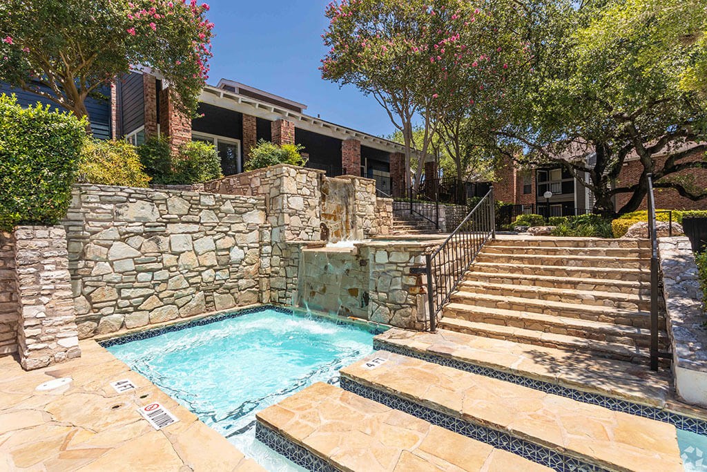a swimming pool with a stone wall and steps leading up to it  at Sunset Canyon, San Antonio, 78232