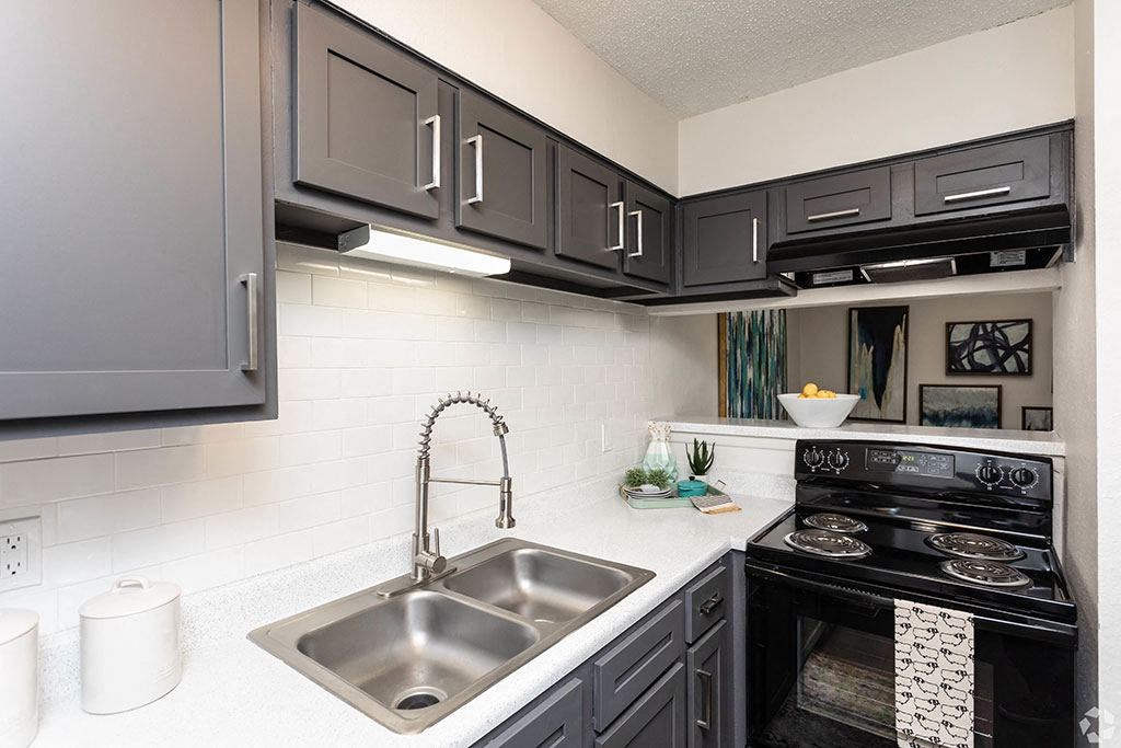 a kitchen with black cabinets and a stainless steel sink  at Sunset Canyon, San Antonio, 78232
