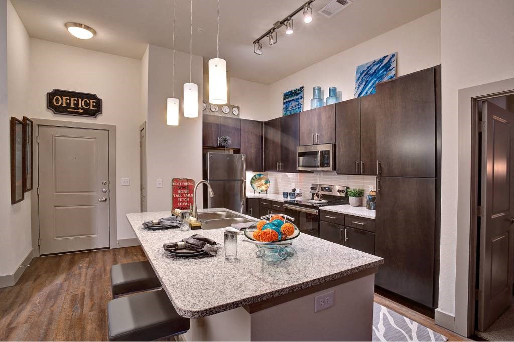 a kitchen with a granite counter top at The Grand at Stonecreek, Texas, 78666