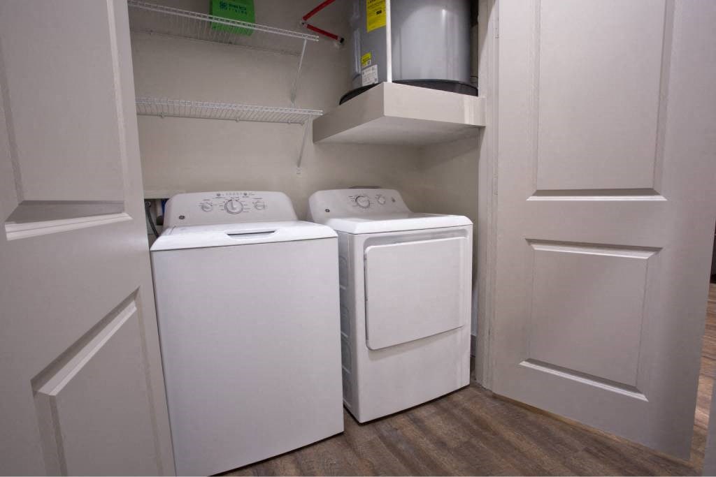 a washer and dryer in a closet with white doors at The Grand at Stonecreek, Texas