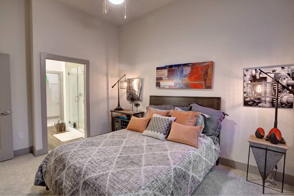 a bedroom with a bed and a door to a bathroom at The Grand at Stonecreek, San Marcos, 78666