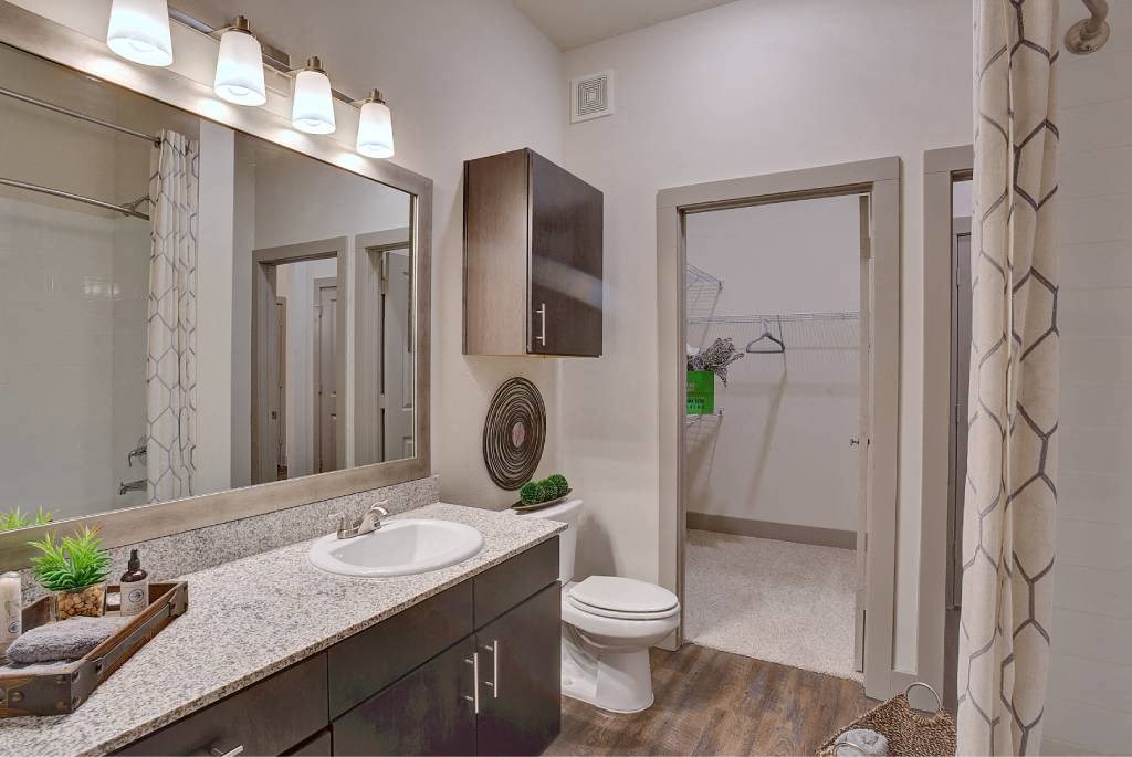 a bathroom with a sink and a toilet and a mirror at The Grand at Stonecreek, San Marcos, TX, 78666