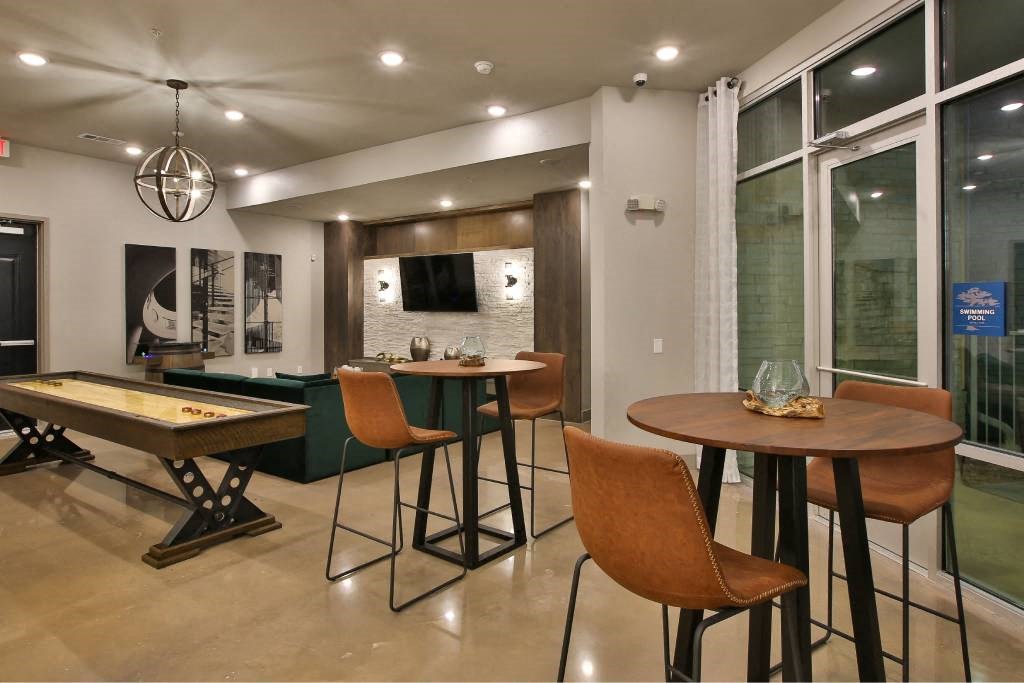 a game room with tables and chairs and a pool table a game room with tables and chairs and a pool table at The Grand at Stonecreek, San Marcos, Texas
