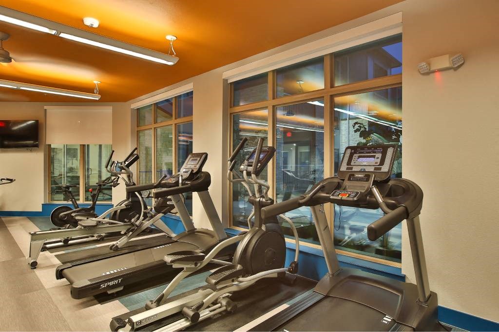a gym with cardio machines and a window at The Grand at Stonecreek, San Marcos, Texas