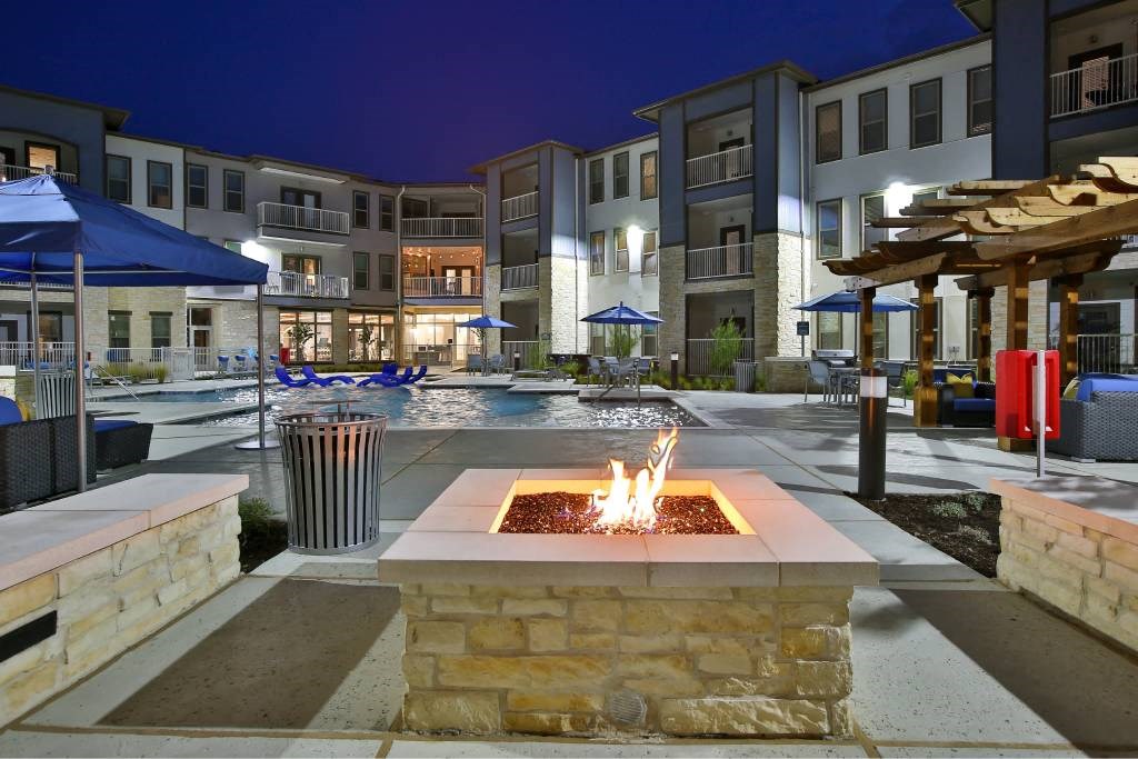 an outdoor area with a fire pit at night at The Grand at Stonecreek, San Marcos, 78666