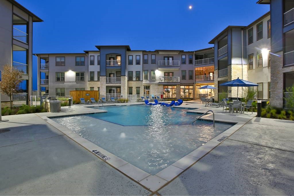 a swimming pool with an apartment building in the background at The Grand at Stonecreek, Texas, 78666