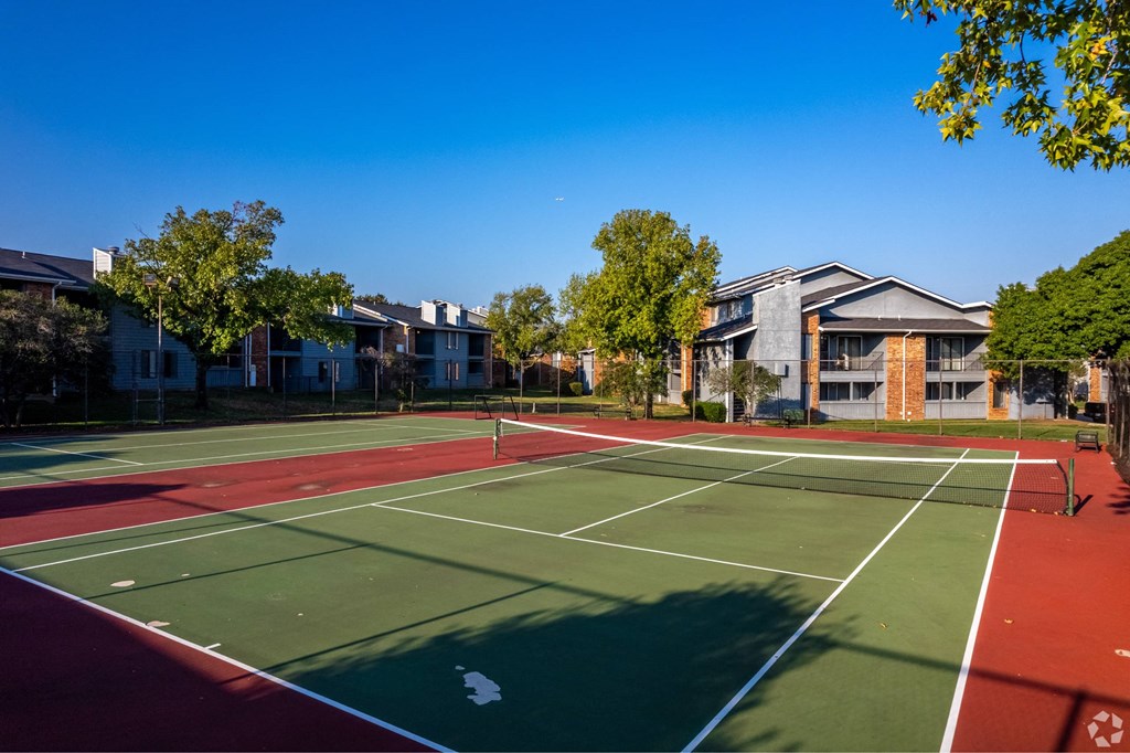 a tennis court with apartments in the background