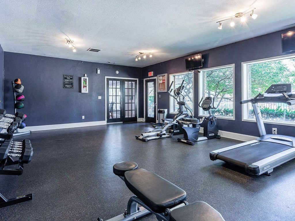 the gym has plenty of exercise equipment and windows
