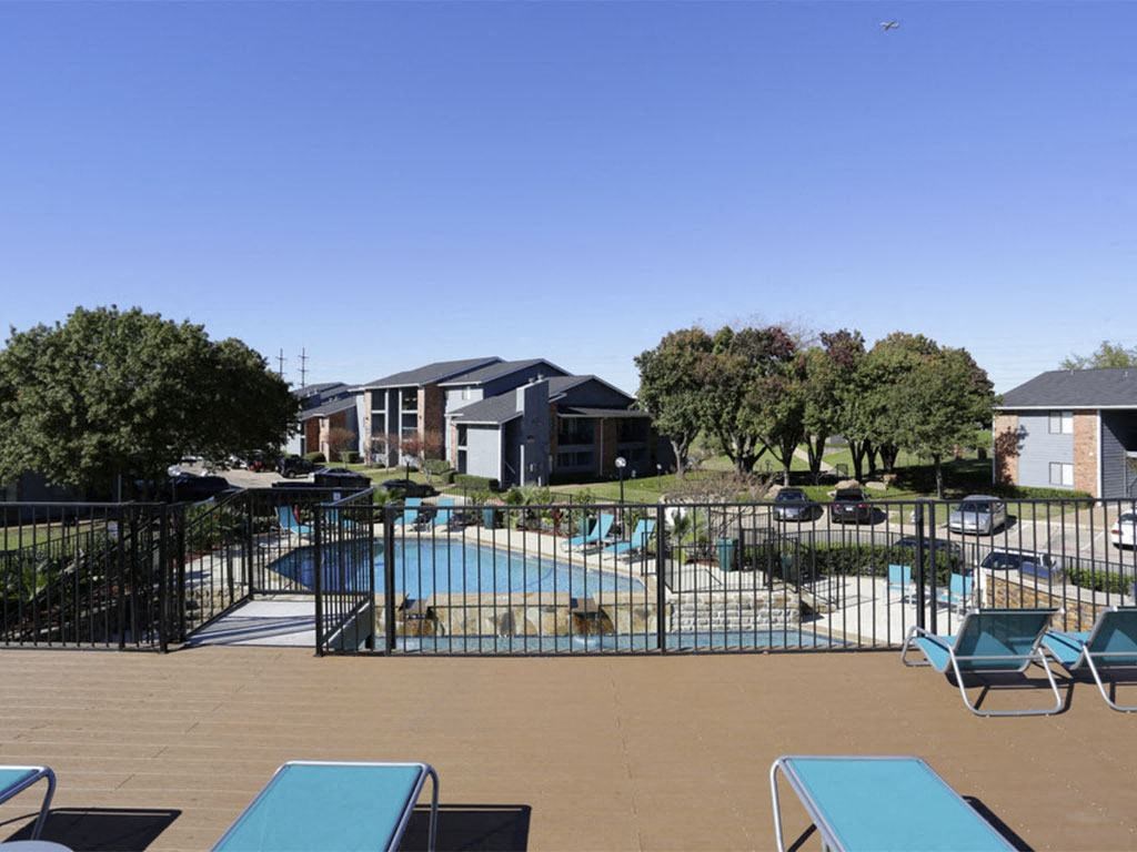 a pool with lounge chairs and a fence