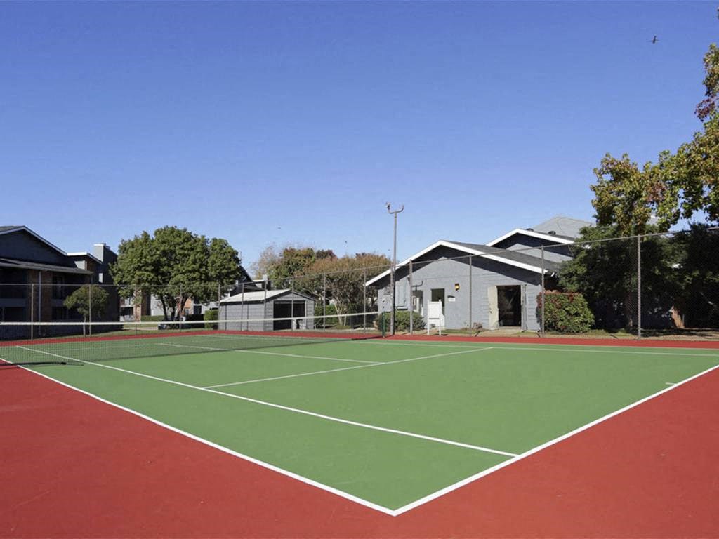 a tennis court with houses and trees in the background