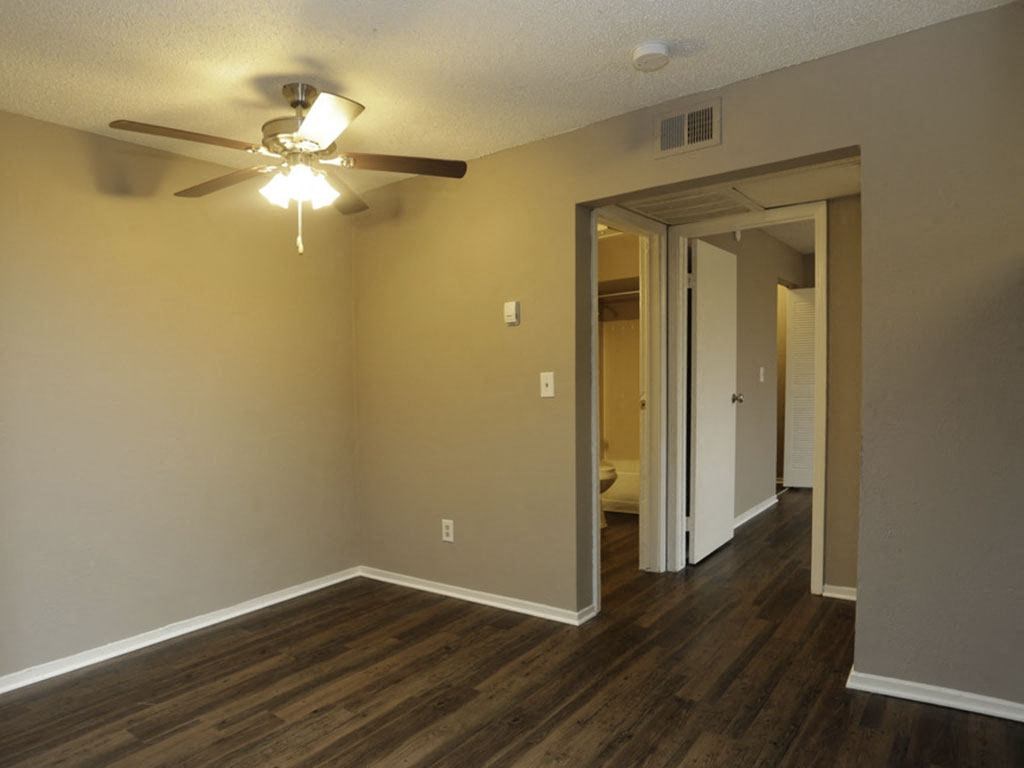 an empty living room with a ceiling fan