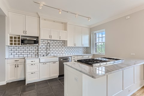 A kitchen with white cabinets and a black and white tiled backsplash.