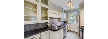 A kitchen with white cabinets and a black countertop.