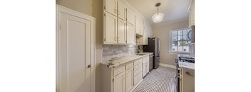 A kitchen with white cabinets and a black refrigerator.