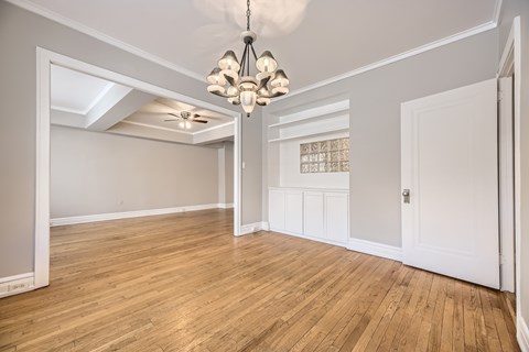 A room with wooden floors and a chandelier hanging from the ceiling.