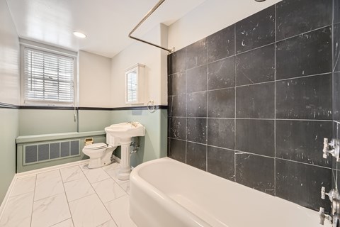 A bathroom with a white tub, toilet, and sink.