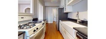 A kitchen with a white stove and black countertops.