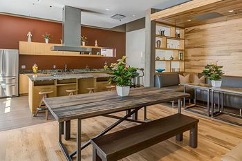 a dining area with a wooden table and a kitchen in the background