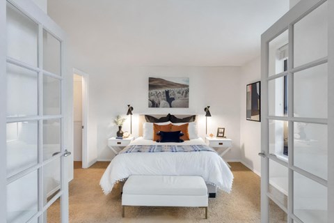 A white bedroom with a large bed and a fireplace.