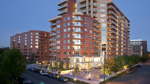 A large red brick apartment building with a parking lot in front.