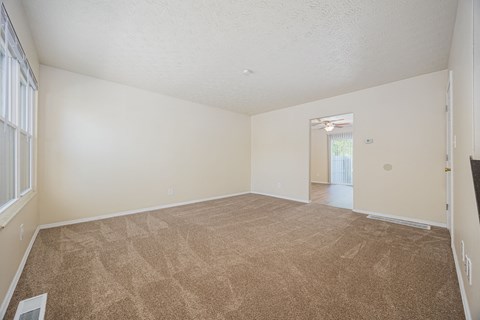 A room with a carpeted floor and a window with blinds.