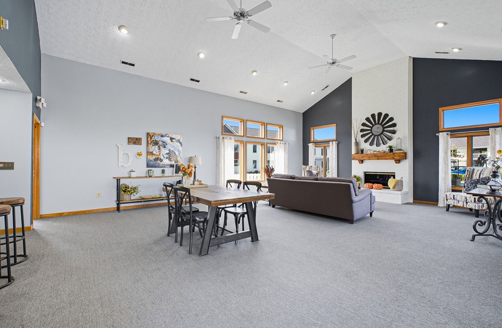 A living room with a grey carpet and a brown couch.