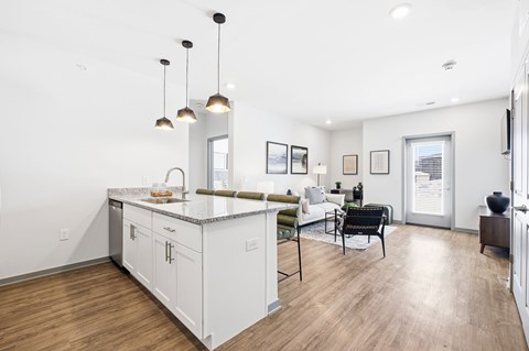 A modern kitchen with white cabinets and a wooden floor.