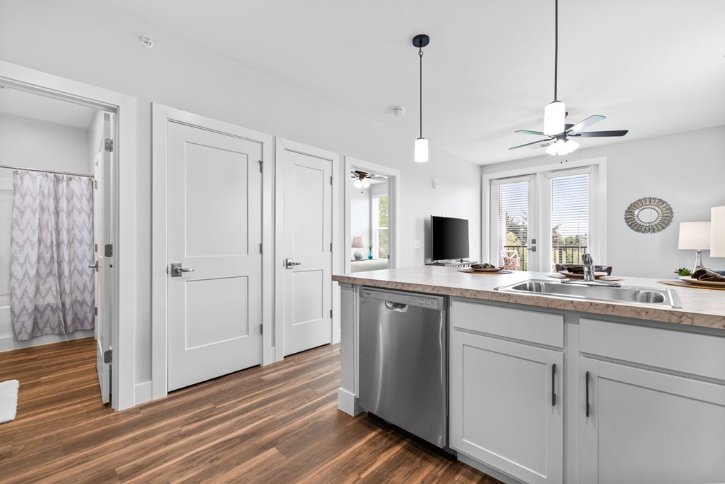 A kitchen with white cabinets and a wooden floor.
