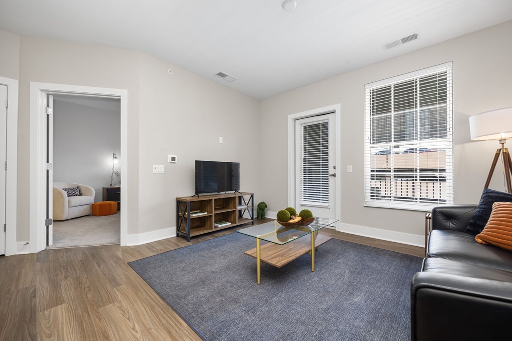 A living room with a black leather couch, a wooden coffee table, and a flat-screen TV.