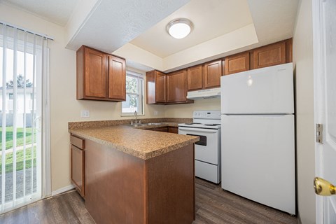 A kitchen with white appliances and wooden cabinets.