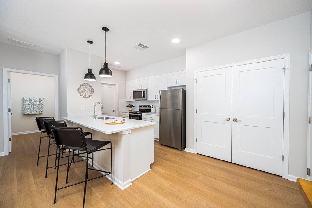 A kitchen with white cabinets and a white island with a counter top.