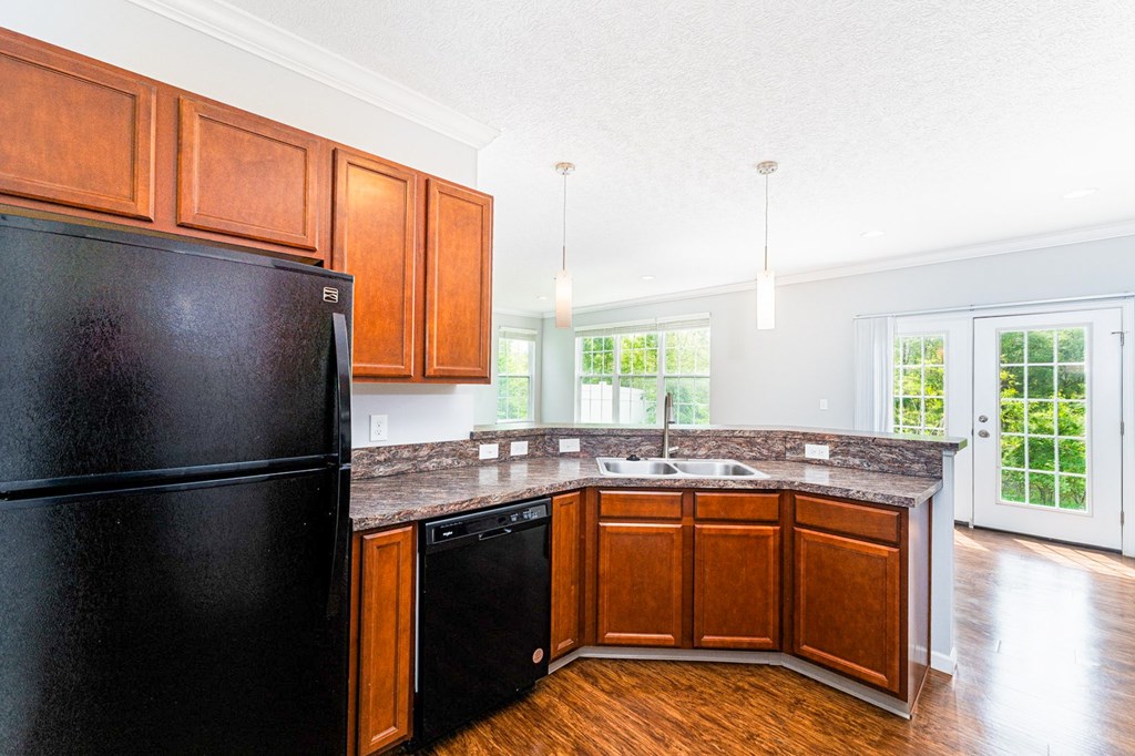 A black fridge in a kitchen with wooden cabinets.