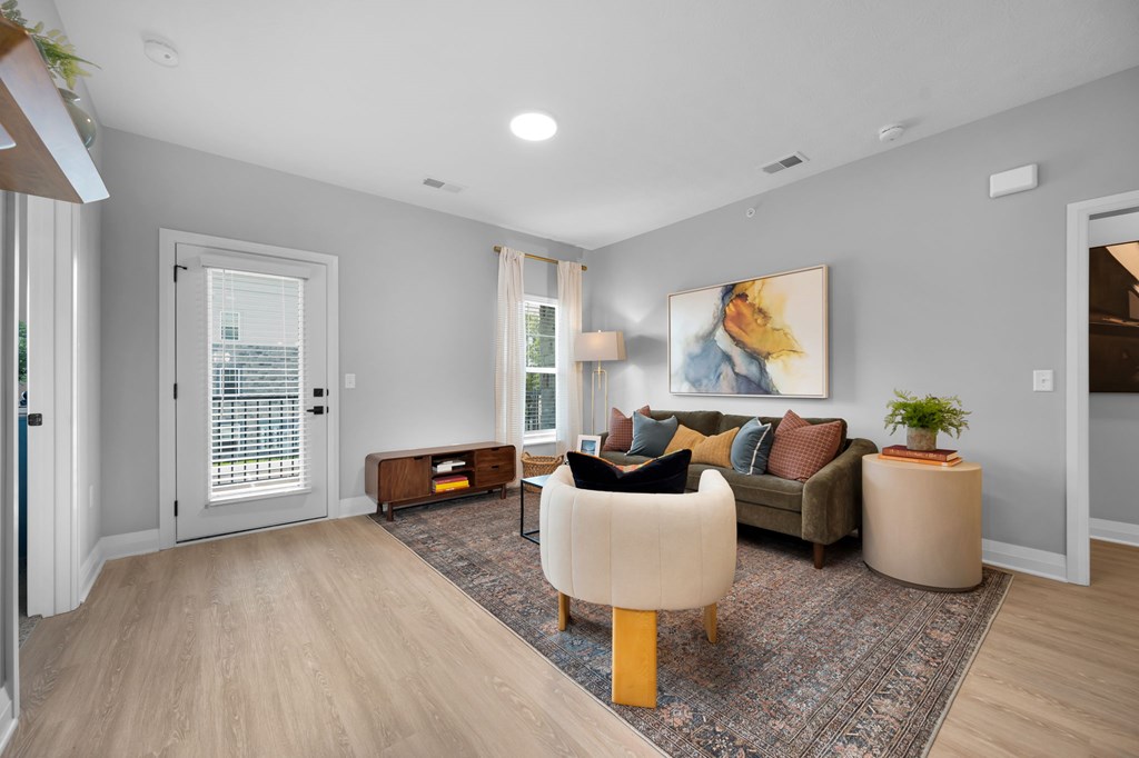 A living room with a brown sofa and a painting on the wall.
