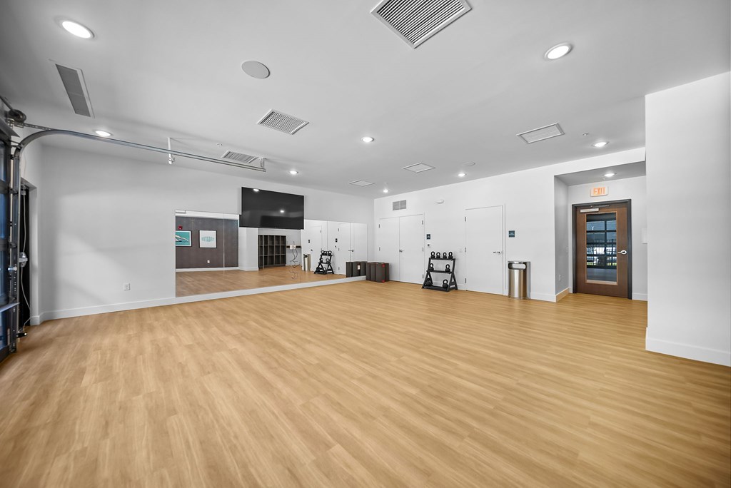 A spacious room with wooden flooring and white walls.