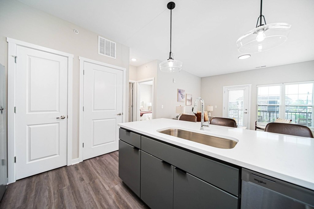 A kitchen with a white counter top and dark wood floors.