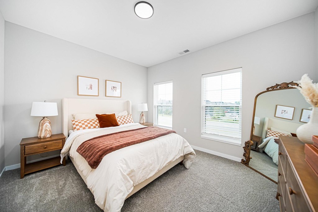 A bedroom with a large bed and a mirror on the wall.