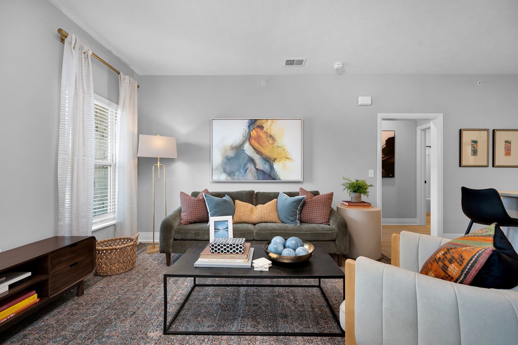 A living room with a couch, a coffee table, and a painting on the wall.