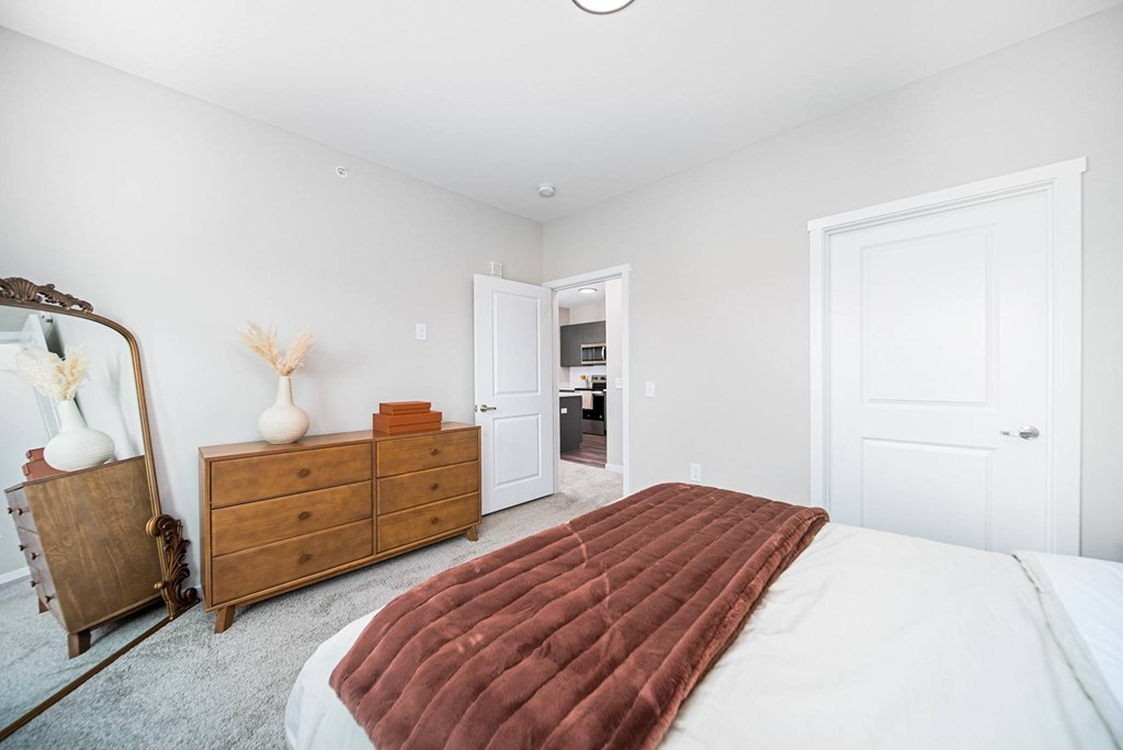 A bedroom with a large bed and a wooden dresser.