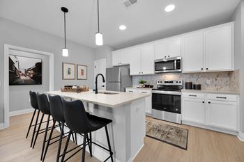 A kitchen with white cabinets and a large island with chairs.