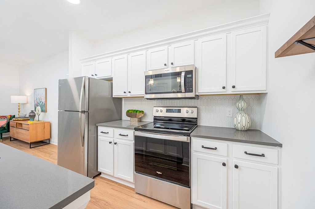 A modern kitchen with white cabinets and stainless steel appliances.