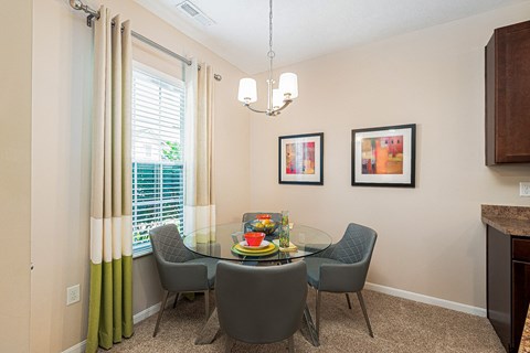 a dining room with a glass table and chairs and a window