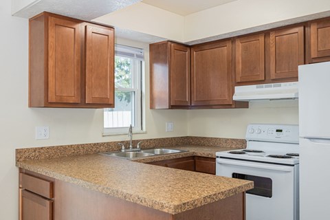 A kitchen with brown cabinets and a white stove.