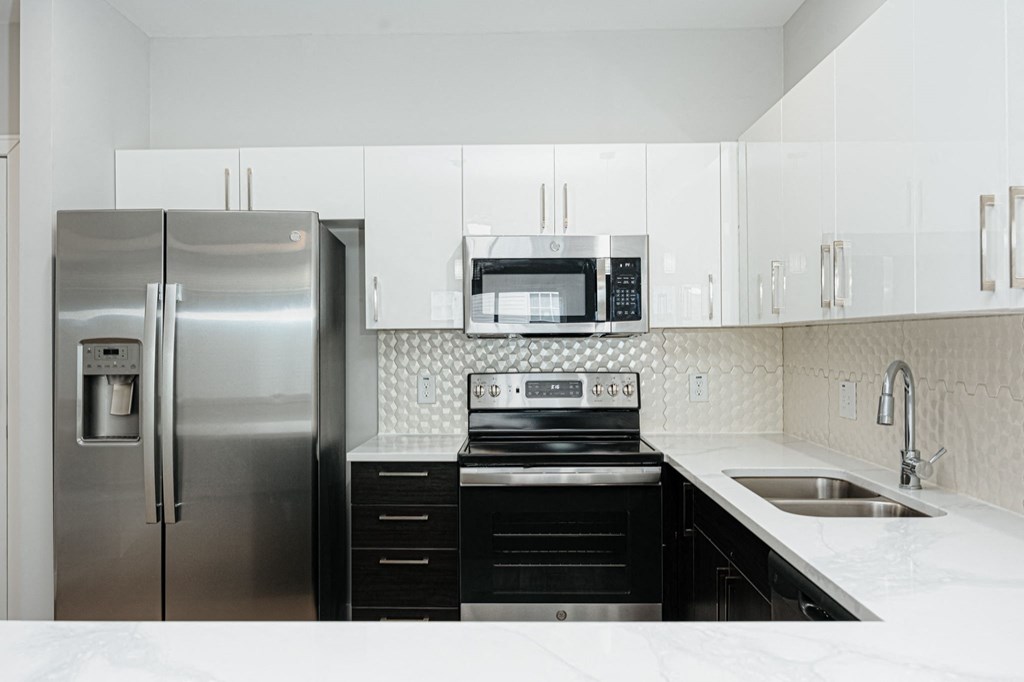 a white kitchen with stainless steel appliances and white counter tops