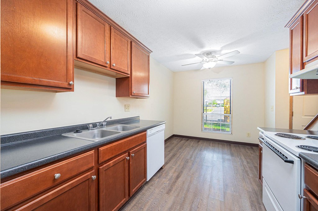 a kitchen with wooden cabinets and white appliances and a window